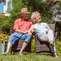 Retired couple sitting outside in the sunshine