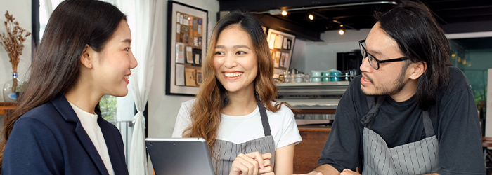 Two women and one male chatting and smiling at table in coffeeshop