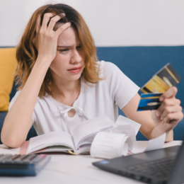 Young woman holding different credit and debit cards in her hand with a confused expression on her face
