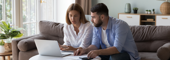 Couple reviewing financial information on a laptop together in their living room