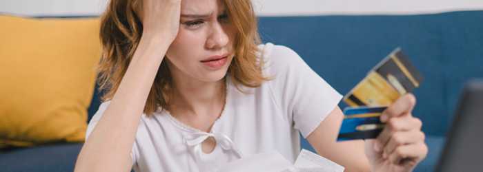 Young woman holding different credit and debit cards in her hand with a confused expression on her face