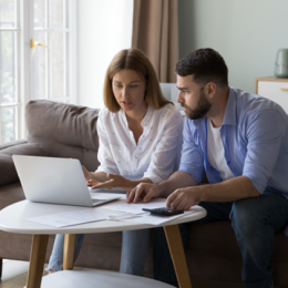 Couple reviewing financial information on a laptop together in their living room