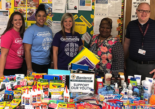 group photo with a table full of school supplies in front