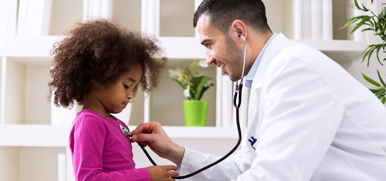 young doctor taking heartbeat of little girl